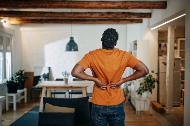 A man standing in his house showing signs of back pain