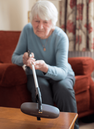 an old lady trying to reach for her glasses with the help of a grabber