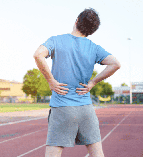 A man standing with both hands on back showing signs of back pain