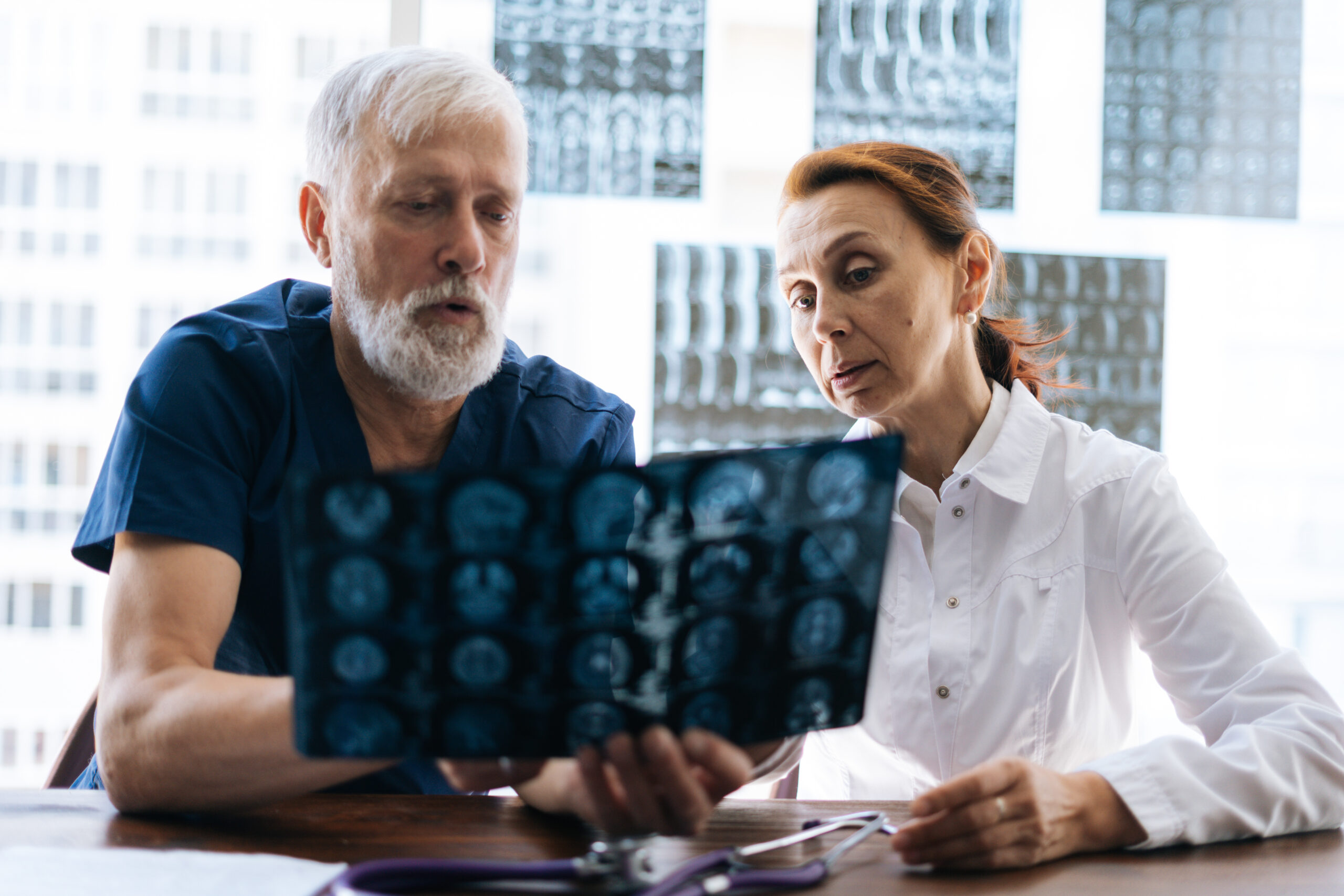 Experienced neurosurgeon Los Angeles reviewing spine MRI scan with patient in modern clinic.