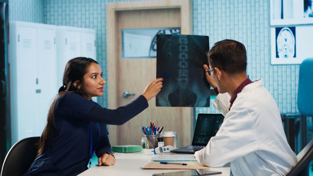 Doctor providing a spine consultation to a patient, reviewing X-ray images for a virtual second opinion spine surgery.