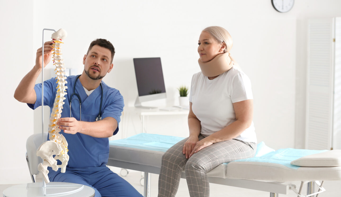 Doctor discussing cervical spine anatomy with a patient to explain how painful is ACDF surgery and post-surgical neck support.