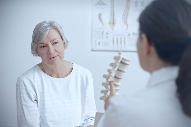 Smiling elderly woman receiving care from a health professional after spine surgery success rate.