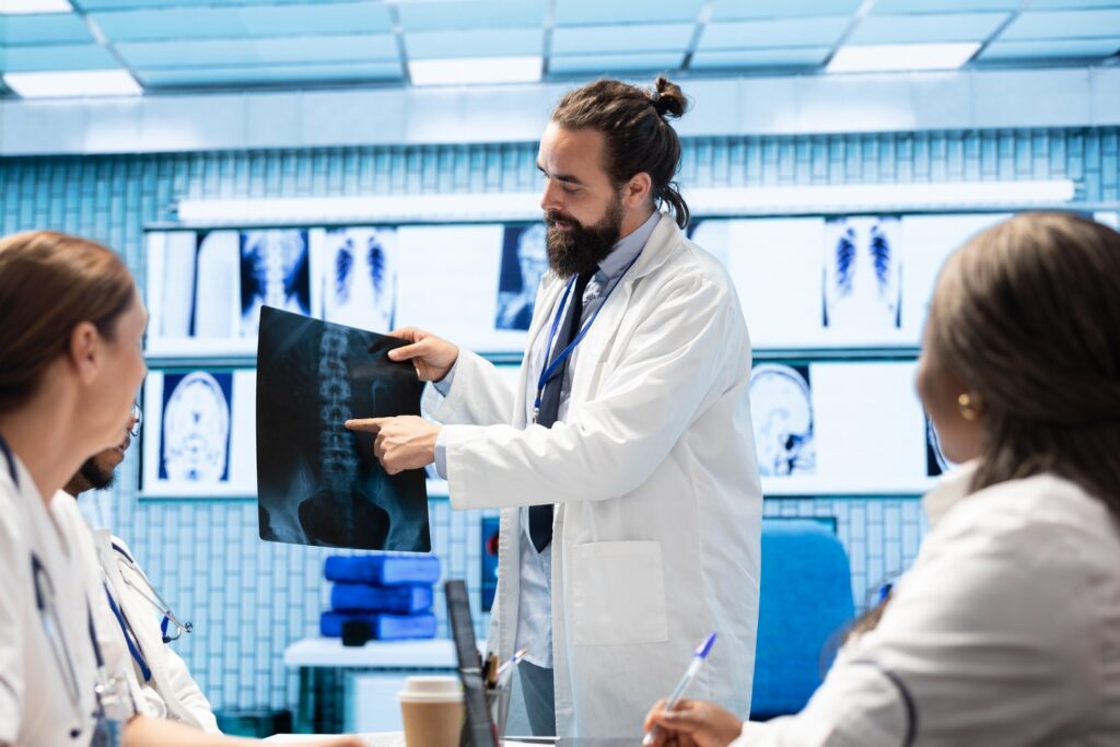 Spinal cord specialist reviewing spinal imaging and X-rays with medical team for diagnosis of spinal cord compression.