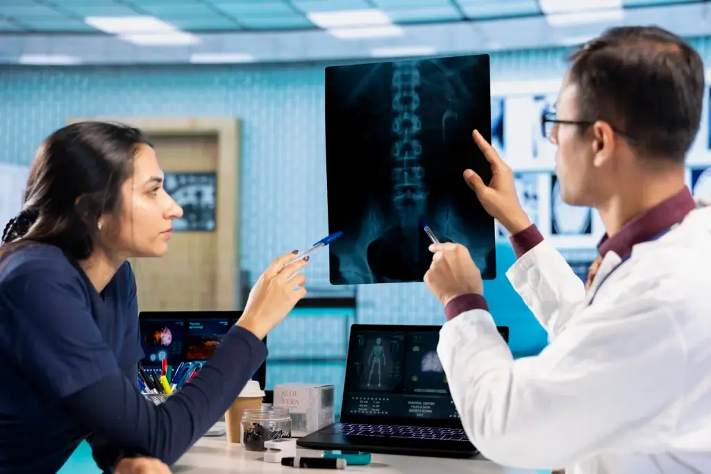 Spinal specialist reviewing patient's spine X-ray imaging to diagnose back condition.