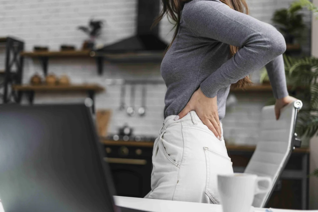 Woman experiencing lower back pain at home seeking good back doctors near me in Los Angeles.